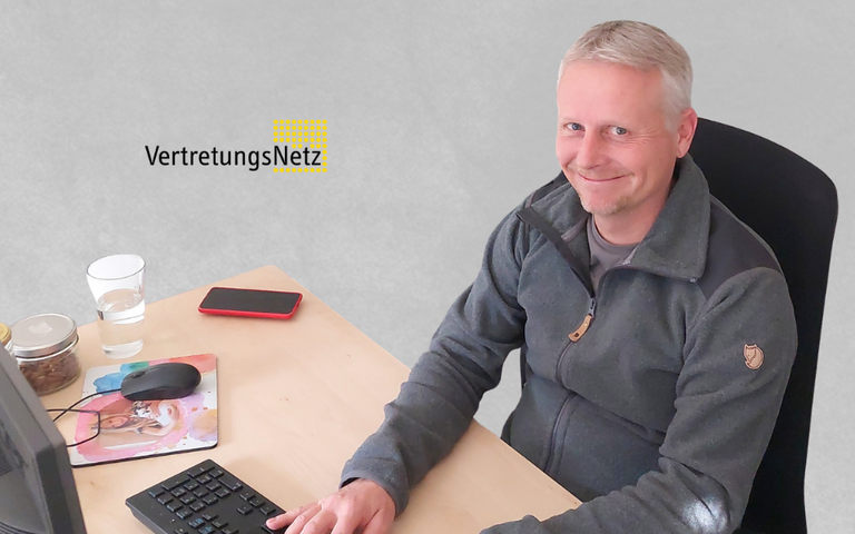 Auf diesem Bild sieht man einen Mann am Schreibtisch