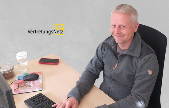 Auf diesem Bild sieht man einen Mann am Schreibtisch