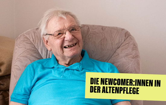 Ein alter Herr sitzt im Lehnstuhl und lacht