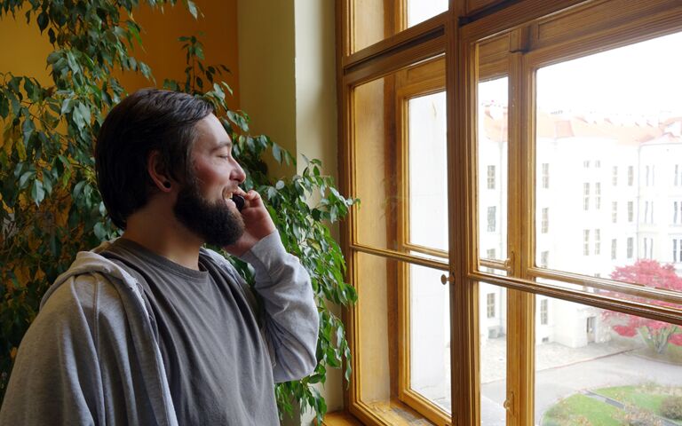 Auf dem Bild telefoniert Raphael Grünzweil und sieht dabei aus dem Fenster