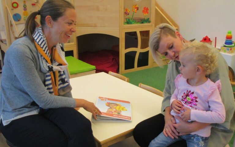 Auf dem Bild sieht man 2 Frauen und ein Kind in einem Kindergarten