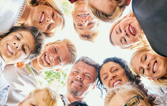 erwachsene Menschen und Kinder schauen von oben in die Kamera