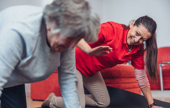 Eine Physiotherapeutin und eine ältere Dame turnen am Boden