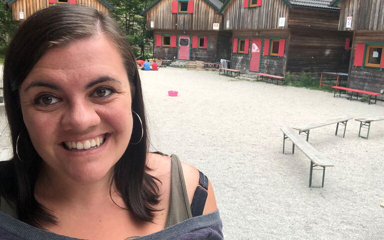 Auf dem Bild sieht links Nina Krautgartner vor verschiedenen Holzhäusern