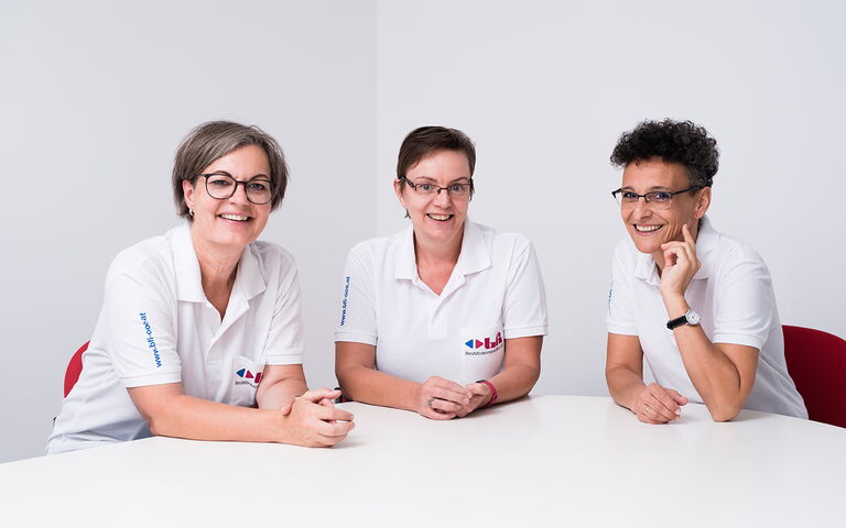 Auf dem Bild sieht man 3 Frauen, die in die Kamera lächeln