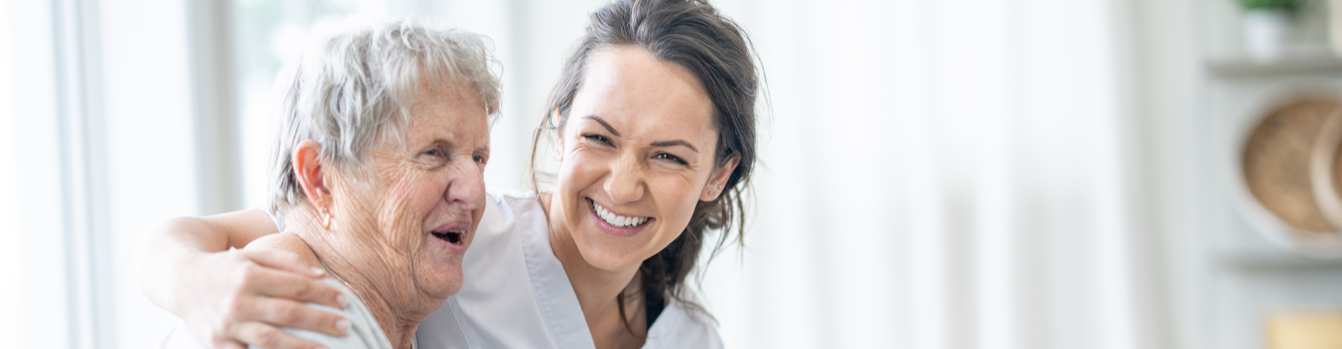eine junge Frau umarmt ein alte Frau, beide lachen