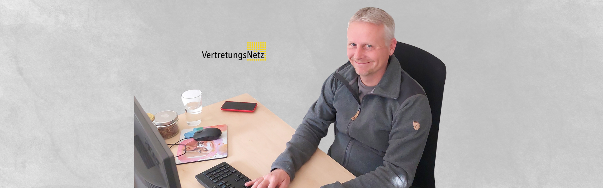 Auf diesem Bild sieht man einen Mann am Schreibtisch
