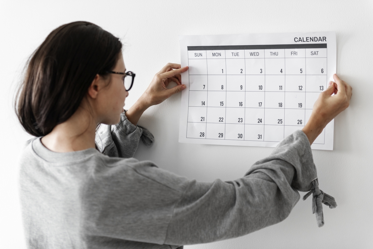 Auf dem Bild hängt eine junge Frau einen Kalender auf