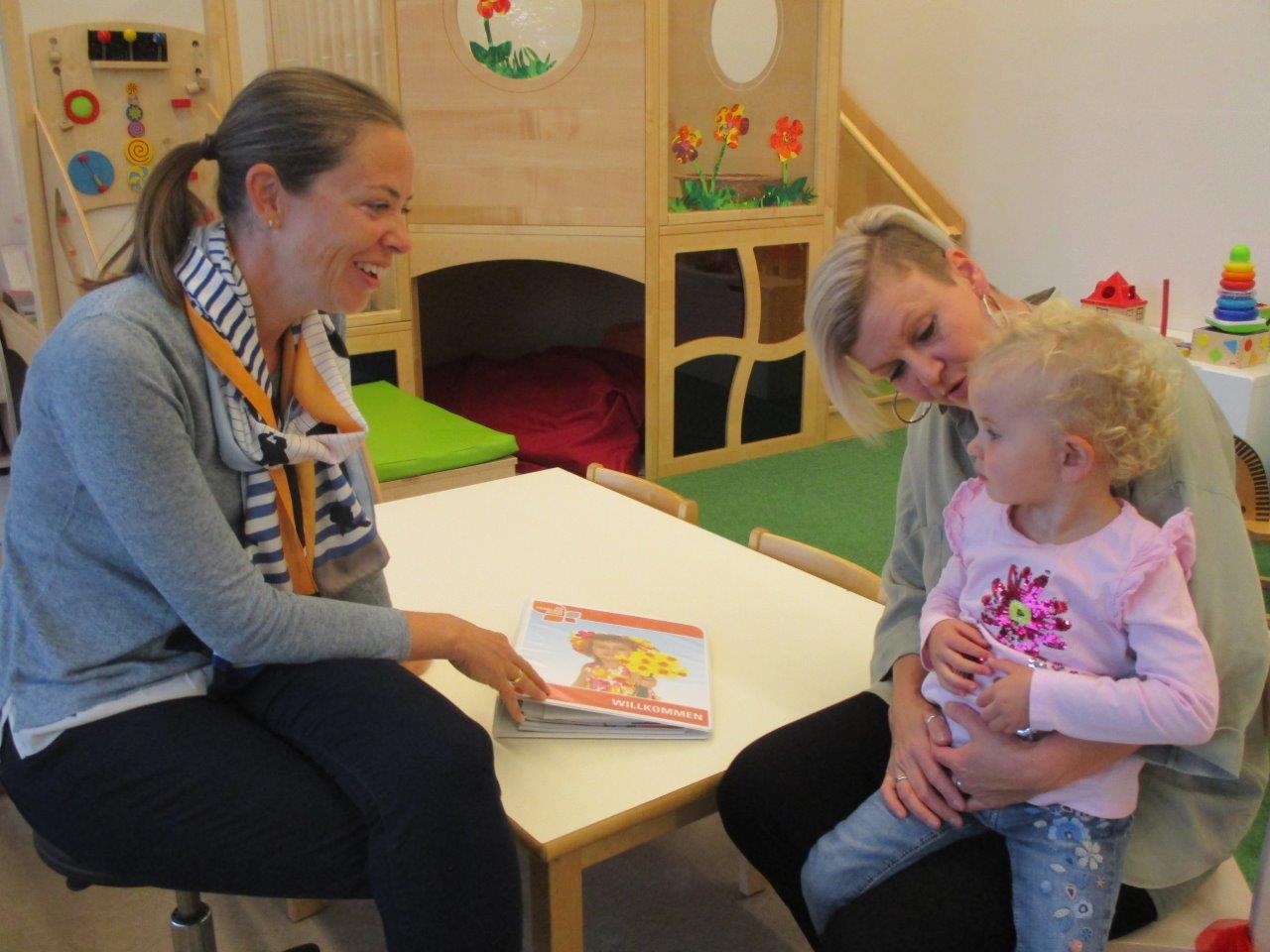 Auf dem Bild sieht man 2 Frauen und ein Kind in einem Kindergarten
